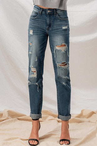 A pair of dark wash boyfriend jeans with distressed holes throughout.
