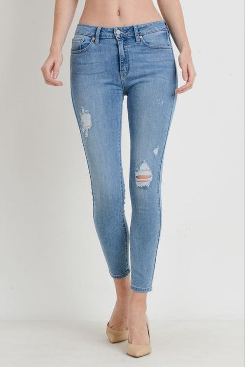A pair of low rise skinny jeans in a light wash and small holes throughout. 
