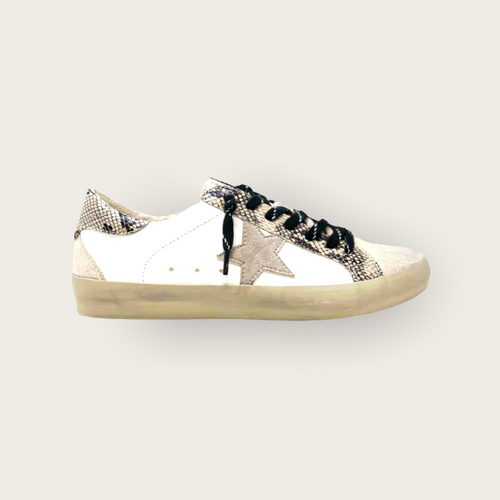 A pair of distressed white leather sneakers with a light grey suede start on the side, black shoe strings, and snakeskin detailing.